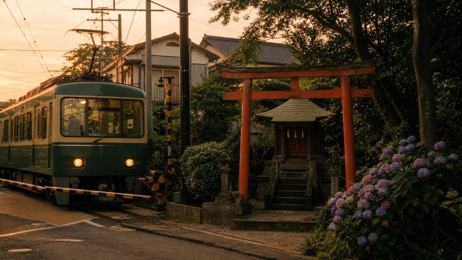 ศาลเจ้าญี่ปุ่นเล็ก ๆ ริมทางรถไฟสายท้องถิ่นในคามาคุระ มีเสาโทริอิสีแดงและรถไฟสีเขียวแล่นผ่าน ท่ามกลางดอกไฮเดรนเยีย